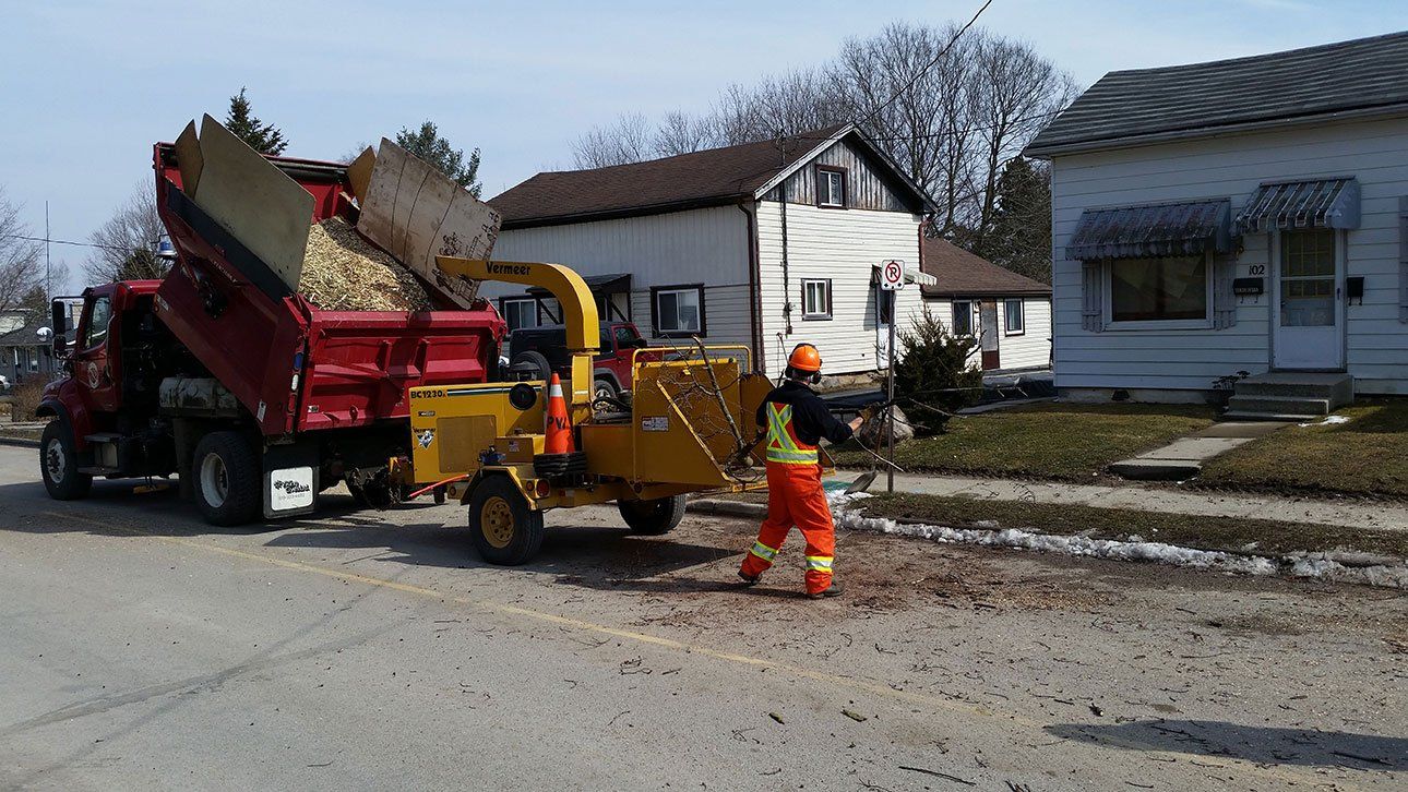 A Town of Ingersoll branded Truck being filled with tree scraps through rear-towed wood chipper