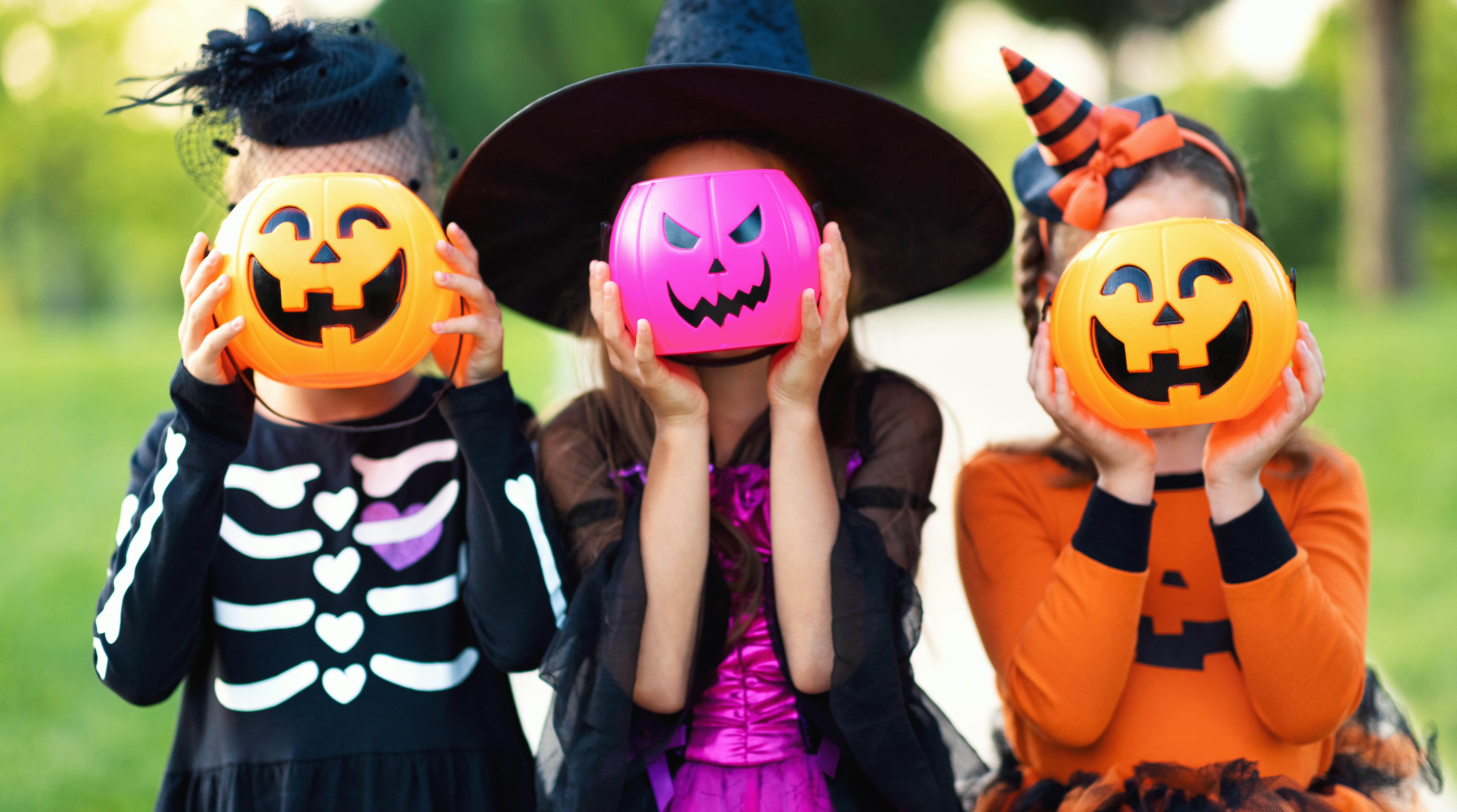 funny children in carnival costumes hide their heads behind buckets pumpkins outdoors